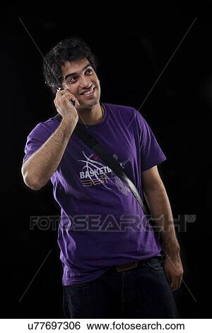 Young man talking on a mobile phone View Large Photo Image Stock Photograph - Young man talking on a mobile phone . Fotosearch