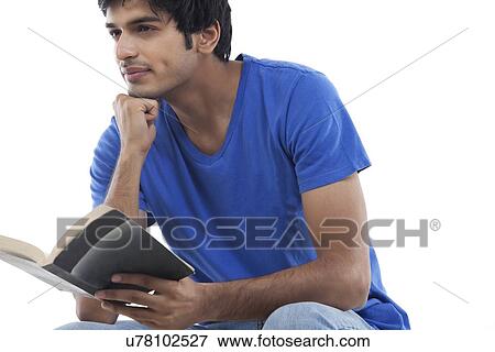 Stock Photo - Young man thinking with book in hand over white background . Fotosearch