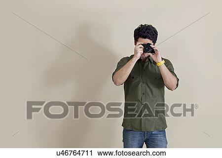 Young man using camera over colored background View Large Photo Image Stock Image - Young man using camera over colored background . Fotosearch