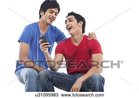 Young men listening to music with headphones against white background View Large Photo Image Stock Image - Young men listening to music with headphones against white background . Fotosearch