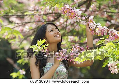 Picture - Young woman admiring flowers on a branch . Fotosearch