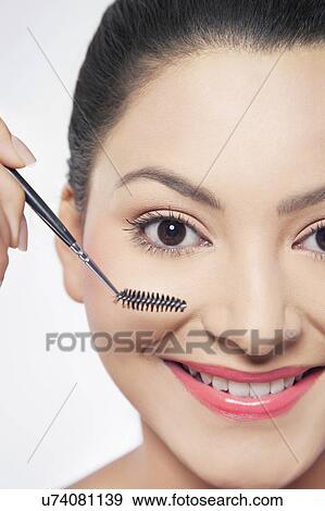 Stock Photo - Young woman applying mascara . Fotosearch