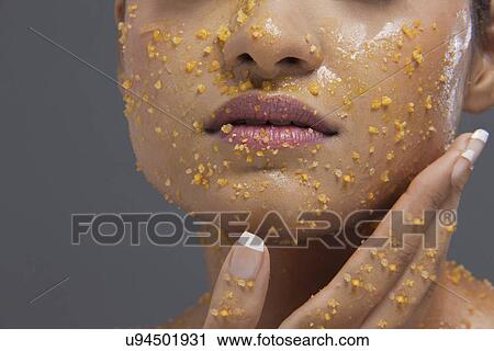 Stock Image - Young woman applying scrub on face . Fotosearch