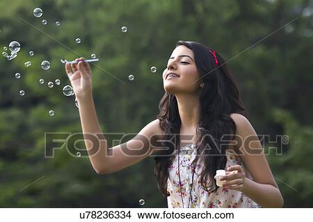 Young woman blowing bubbles in a park View Large Photo Image Picture - Young woman blowing bubbles in a park . Fotosearch
