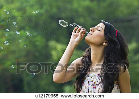 Stock Photography - Young woman blowing bubbles in a park . Fotosearch
