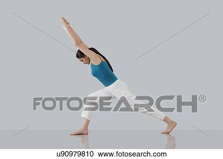 Stock Image - Young woman doing stretching exercise isolated over gray background. Fotosearch