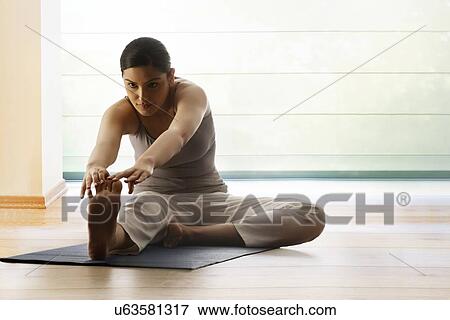 Young woman doing stretching exercise on yoga mat View Large Photo Image Stock Photo - Young woman doing stretching exercise on yoga mat. Fotosearch