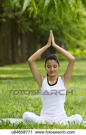 Stock Image - Young woman doing yoga with hands in prayer position . Fotosearch