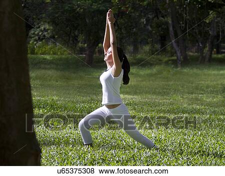 Stock Photo - Young woman doing yoga with hands outstretched . Fotosearch