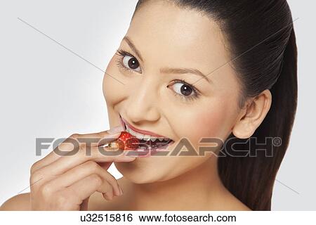 Young woman eating a strawberry View Large Photo Image Stock Photograph - Young woman eating a strawberry . Fotosearch