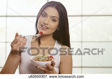 Young woman eating bean sprouts and cherry tomatoes against glass window View Large Photo Image Stock Photo - Young woman eating bean sprouts and cherry tomatoes against glass window . Fotosearch