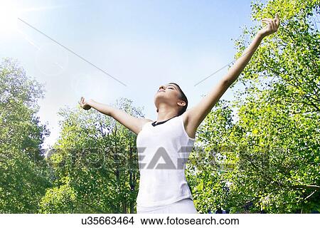 Picture - Young woman enjoying nature in a park . Fotosearch