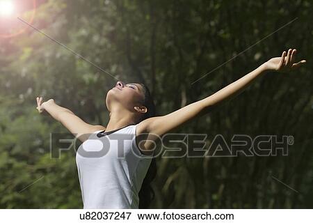 Stock Photo - Young woman enjoying nature in a park . Fotosearch
