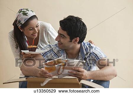 Young woman giving cupcake to man at home View Large Photo Image Stock Photo - Young woman giving cupcake to man at home . Fotosearch