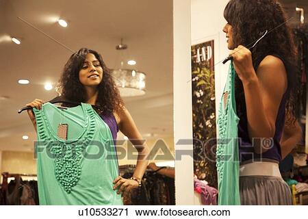 Young woman holding up dress in front of mirror View Large Photo Image Stock Image - Young woman holding up dress in front of mirror . Fotosearch