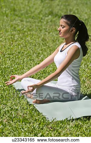 Young woman in lotus position meditating in a park View Large Photo Image Stock Photography - Young woman in lotus position meditating in a park . Fotosearch