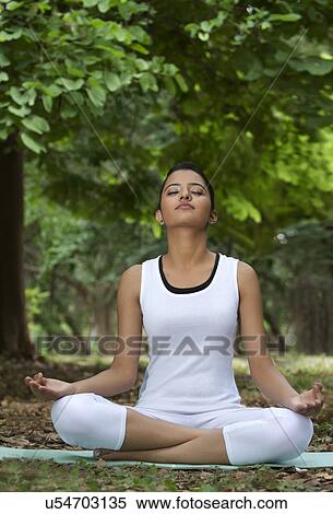Young woman in lotus position meditating in a park View Large Photo Image Stock Photography - Young woman in lotus position meditating in a park . Fotosearch
