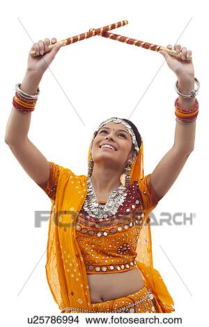 Young woman in traditional wear performing Dandiya Raas over white background View Large Photo Image Picture - Young woman in traditional wear performing Dandiya Raas over white background. Fotosearch