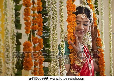 Stock Photo - Young woman in traditional wear standing near garlands . Fotosearch