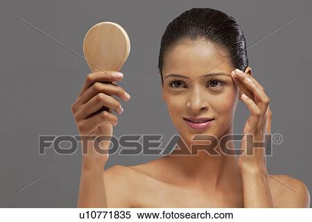 Stock Photography - Young woman looking at self in mirror . Fotosearch