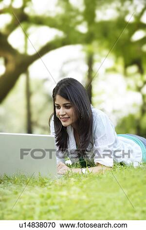 Young woman lying on green grass and using laptop View Large Photo Image Stock Image - Young woman lying on green grass and using laptop . Fotosearch