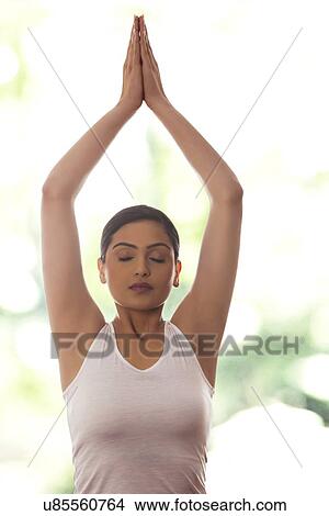 Young woman meditating against glass window View Large Photo Image Picture - Young woman meditating against glass window. Fotosearch