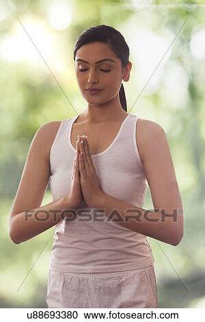 Stock Image - Young woman meditating against glass window. Fotosearch
