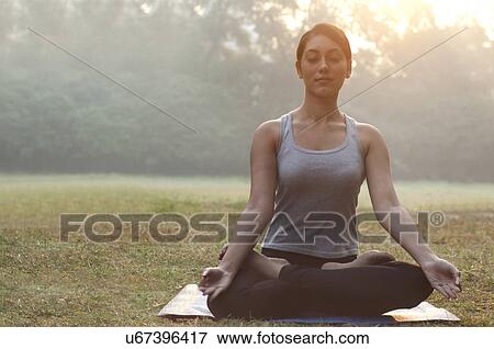 Young woman meditating in park View Large Photo Image Stock Photo - Young woman meditating in park . Fotosearch
