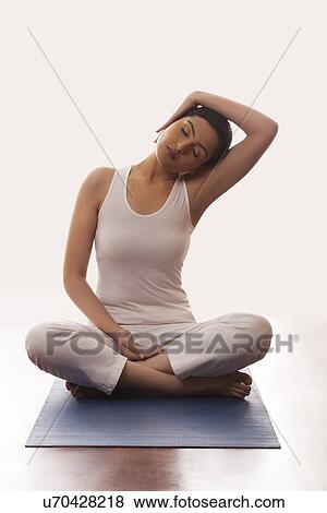 Stock Photo - Young woman meditating on mat. Fotosearch