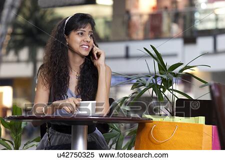 Stock Photography - Young woman on call while drinking coffee . Fotosearch