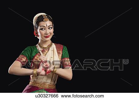 Stock Photograph - Young woman performing Bharatanatyam over black background. Fotosearch