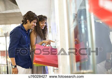 Young woman pointing with smiling man at shopping mall View Large Photo Image Stock Photo - Young woman pointing with smiling man at shopping mall . Fotosearch
