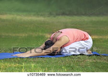 Stock Photo - Young woman practicing yoga in lawn . Fotosearch