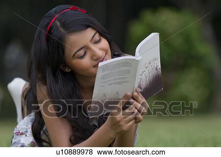 Young woman reading a book in a park View Large Photo Image Stock Photo - Young woman reading a book in a park . Fotosearch