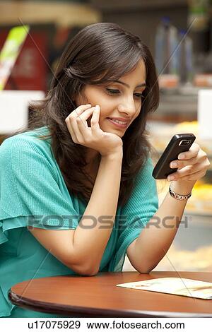 Stock Photo - Young woman reading text message on cell phone . Fotosearch