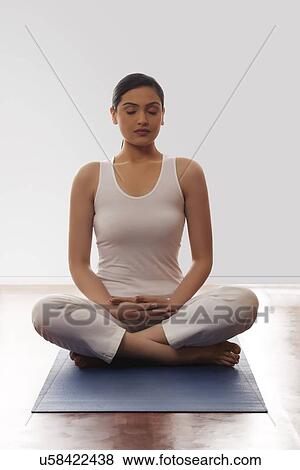 Young woman sitting in lotus position on mat View Large Photo Image Stock Photo - Young woman sitting in lotus position on mat. Fotosearch