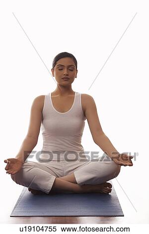 Stock Photography - Young woman sitting in lotus position on mat. Fotosearch