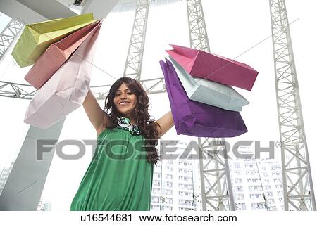 Young woman smiling while showing her shopping bags View Large Photo Image Stock Image - Young woman smiling while showing her shopping bags . Fotosearch