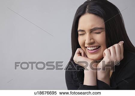 Young woman smiling with eyes closed over colored background View Large Photo Image Stock Photography - Young woman smiling with eyes closed over colored background . Fotosearch