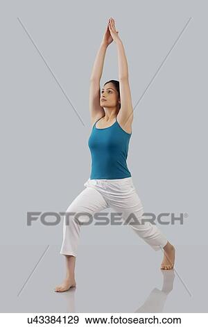 Stock Photo - Young woman stretching arms upwards isolated over gray background. Fotosearch