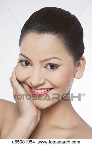 Picture - Young woman touching her face over white background . Fotosearch