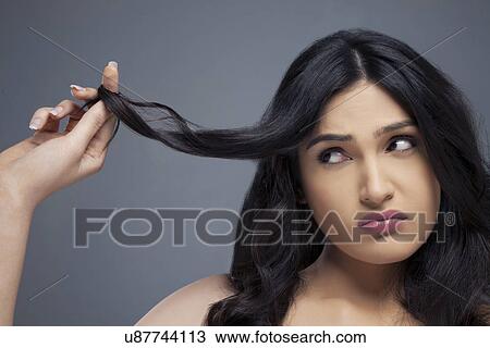 Young woman twisting hair finger over colored background View Large Photo Image Stock Image - Young woman twisting hair finger over colored background . Fotosearch