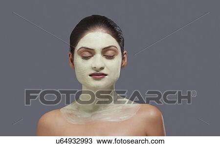 Stock Image - Young woman with facial mask on her face . Fotosearch