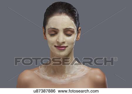 Young woman with facial mask on her face over colored background View Large Photo Image Stock Photograph - Young woman with facial mask on her face over colored background . Fotosearch