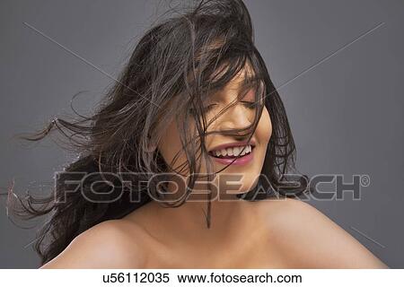Young woman with hair blowing over face against colored background View Large Photo Image Stock Photography - Young woman with hair blowing over face against colored background . Fotosearch