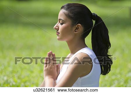 Stock Image - Young woman with hands in prayer position . Fotosearch