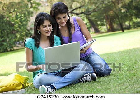 Stock Image - Young women taking notes from laptop . Fotosearch