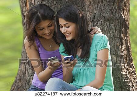 Stock Photo - Young women using cell phone . Fotosearch
