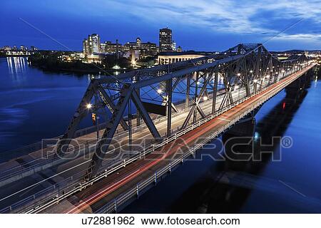 Stock Image - Alexandra Bridge and river bank at dusk. Fotosearch