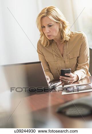 Business woman using laptop and cell phone View Large Photo Image Stock Image - Business woman using laptop and cell phone. Fotosearch